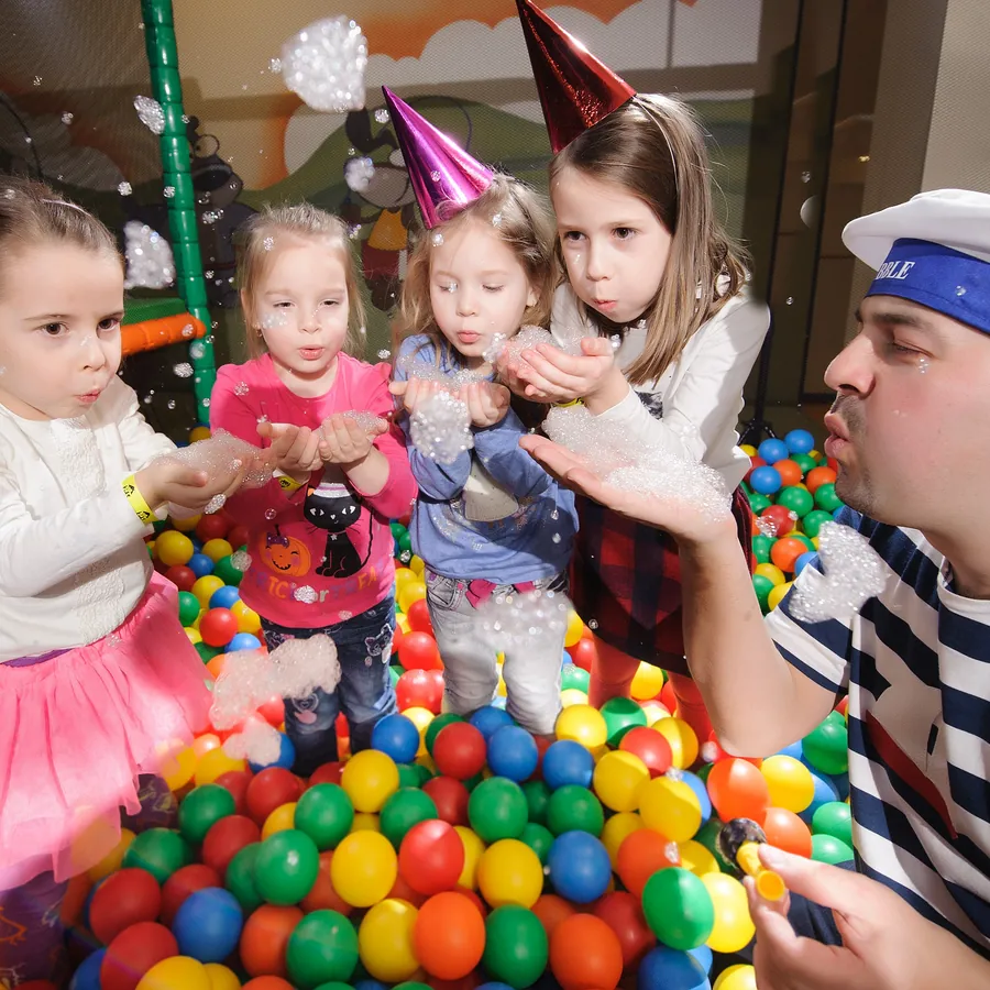 Deti v narodeninových čiapkach fúkajú bublinovú penu