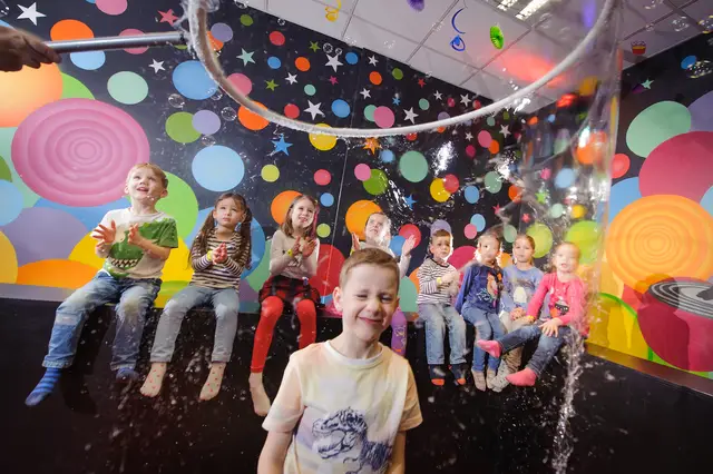 Children sitting on the edge of the bubble pool amid bubble foam